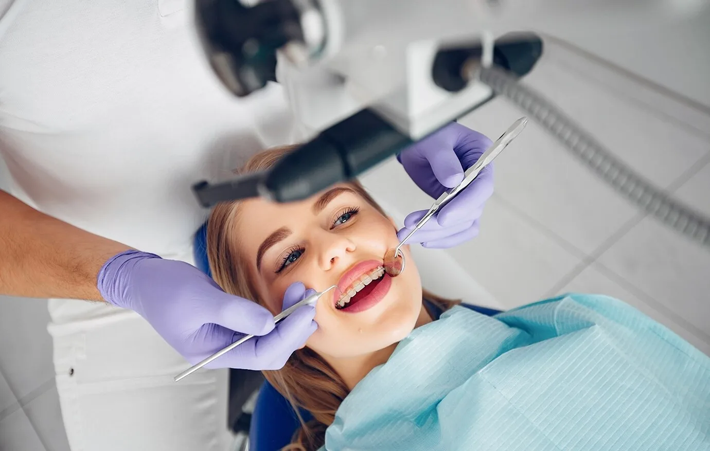 Patient wearing braces having her teeth checked by a dentist