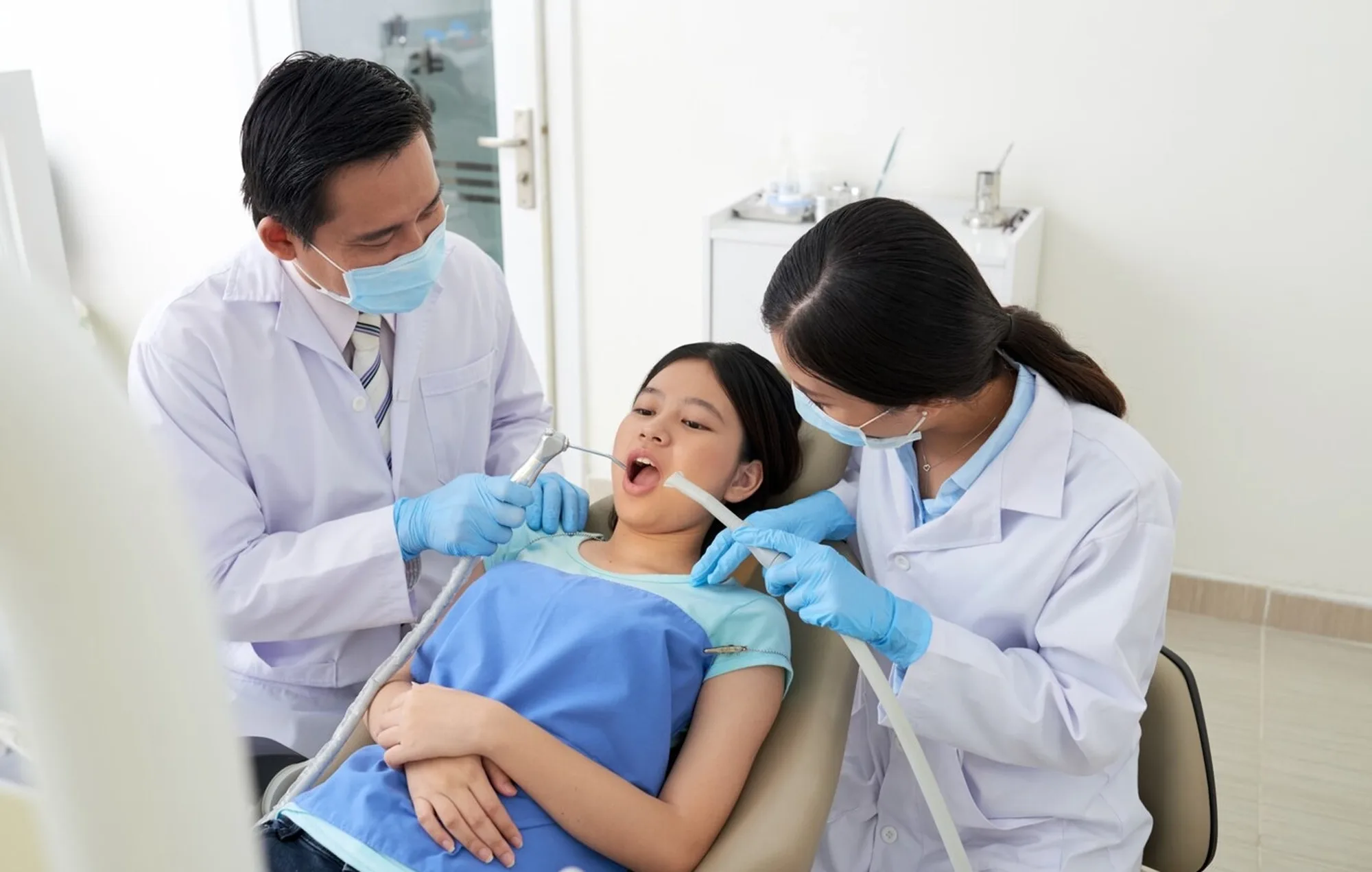 Dentist and assistant treating a young patient in the dental chair