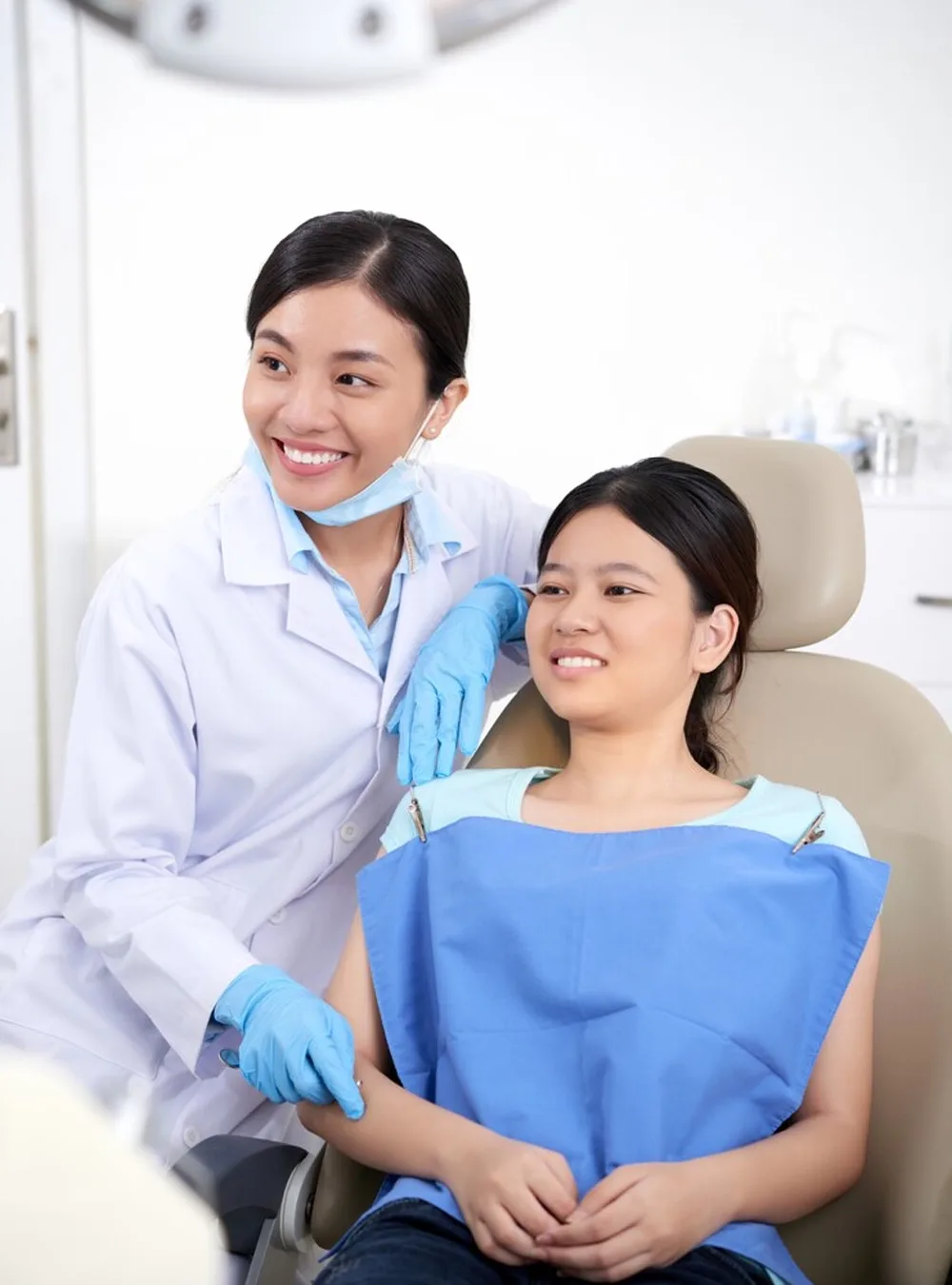 Dentist reassuring a smiling young patient in the dental chair