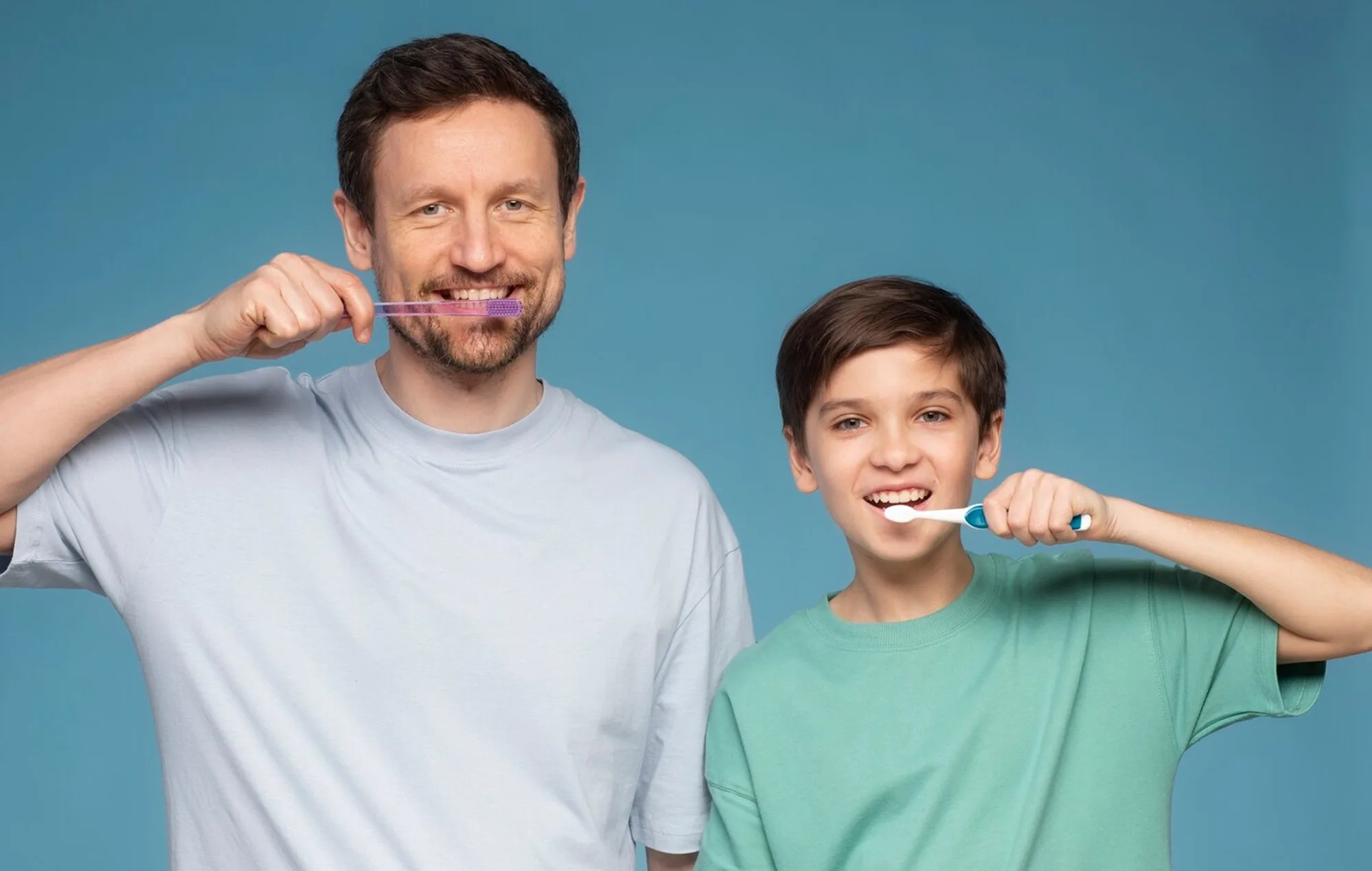 Father and son brushing their teeth together