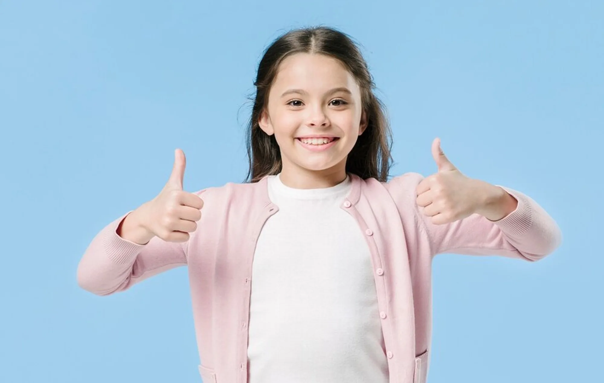Smiling girl giving two thumbs up after a dental visit